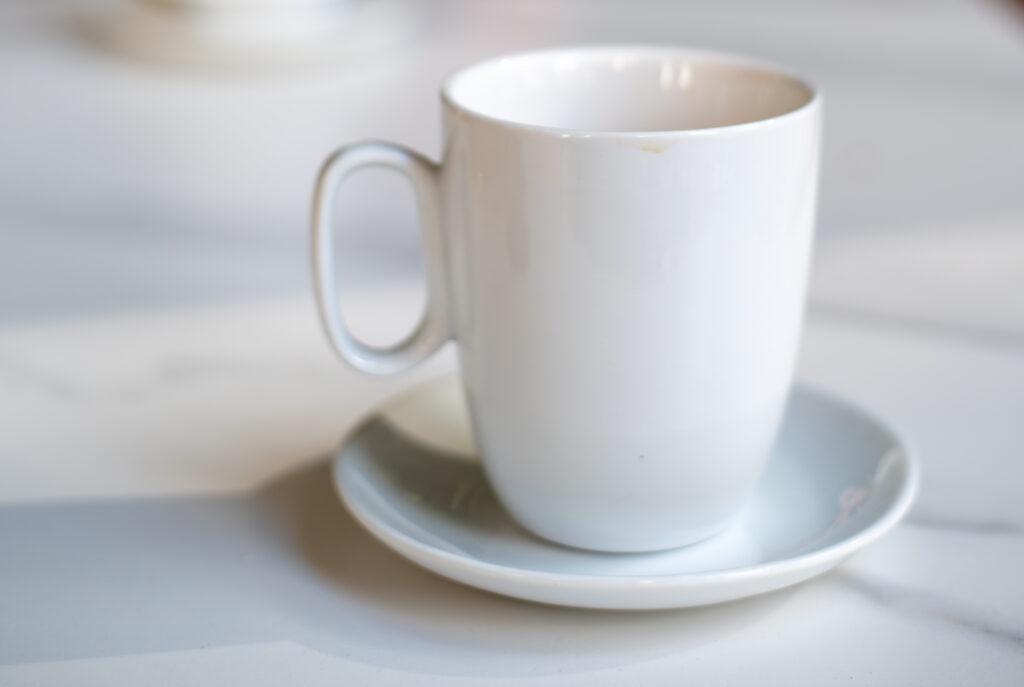 A white porcelain cup on top of a white saucer on top of a table