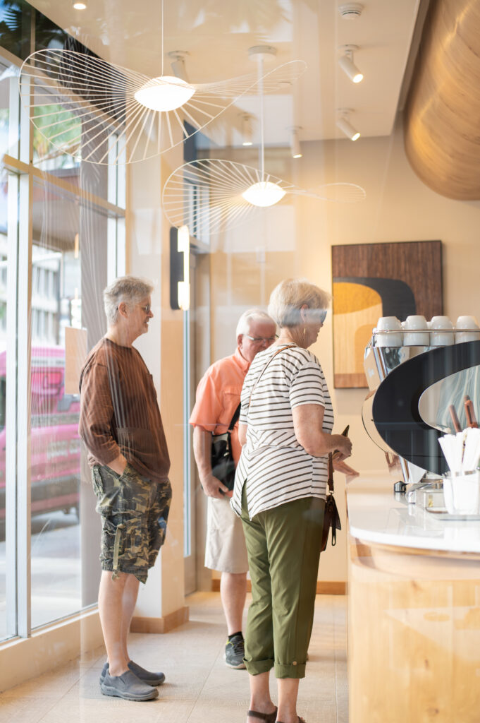 A elderly woman and two elderly man photographed through a window in a coffee shop 