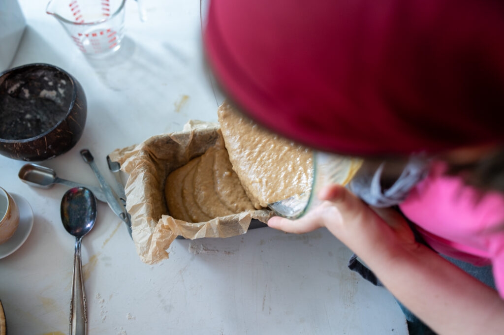 pouring banana bread dough into loaf pan